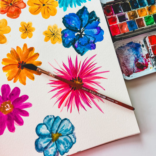 Colorful floral paintings on a watercolour paper with watercolor paints and palette.